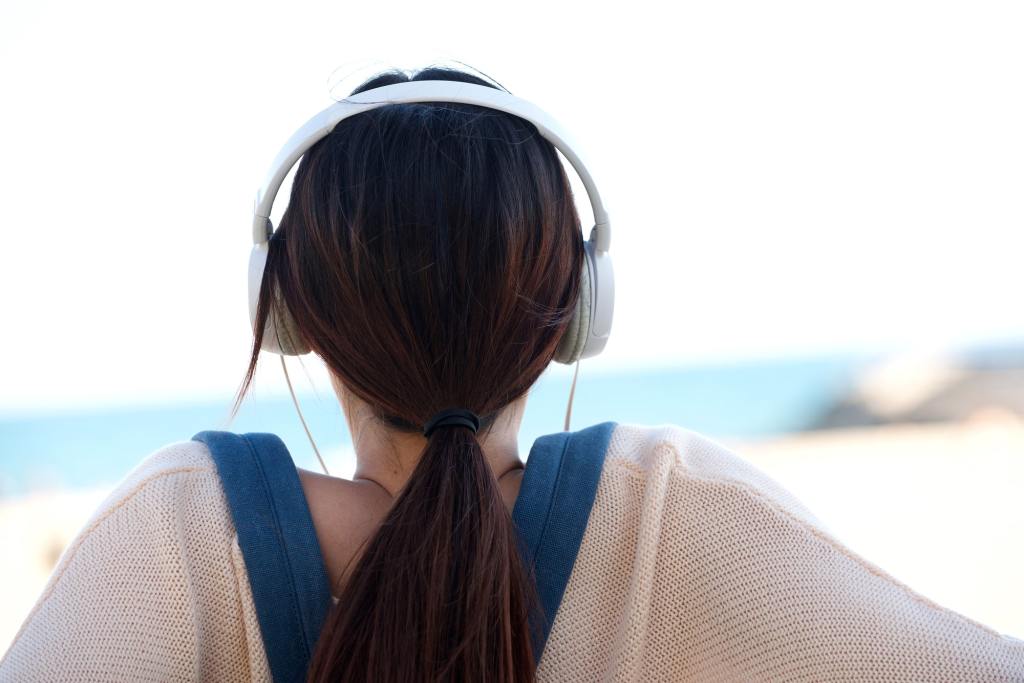 Woman sitting by beach with headphones